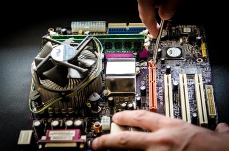 user using screw driver on computer motherboard components for maintenance and repair